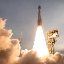 A rocket being launched, with a huge plume of smoke and fire shooting out of it.